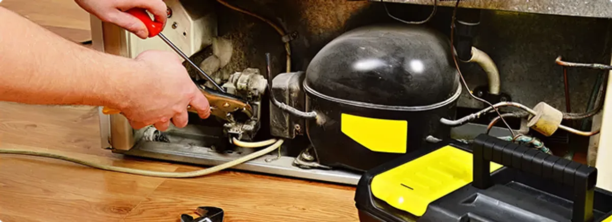 Refrigerator repair technician fixing the compressor and wiring in Comstock Park, MI